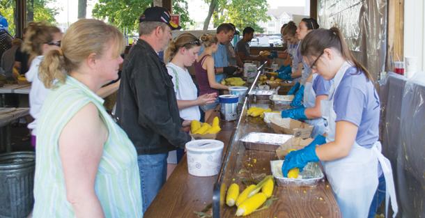 Corn fest volunteers butter corn for festival patrons.