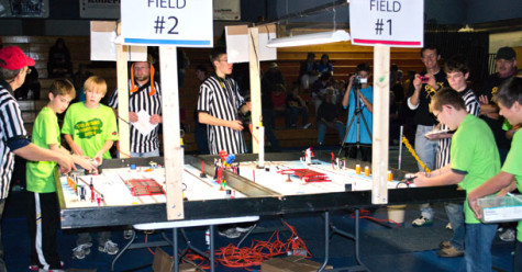 Referees congregate near the Lego robot playing field.
