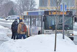 Students stand out in the cold weather as they wait at the bus stop near the Truax campus to board a Madison Metro bus.