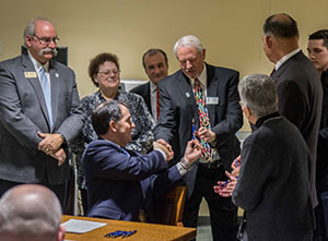 Gov. Scott Walker (seated) signs bill at the Health Education building as Madison College dignitaries look on.