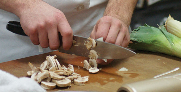 Mushrooms are sliced in the kitchen in preparation for a meal to be served in the gourmet dining room.