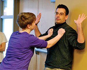 Ed Glimme demonstrates self-defense with partner Caitlin Beigler what to do if pinned against a wall.