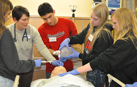 Students practice respiratory care on a dummy during a health care class.