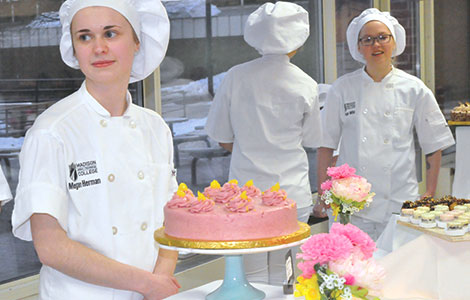 Megan Herman, left, waits to assist visitors at the Baking and Decorative Arts program dessert tasting event held on Feb. 9 in the Truax campus cafeteria. The desserts served at the event were prepared by teams of students.