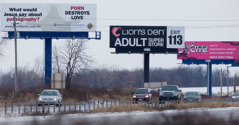 Motorists pass a billboard advocating against pornography next to a series of billboards for the Lions Den and Xcite adult entertainment stores on Thursday, Jan. 8, 2015, along Hwy. 41 in North Fond du Lac, Wis.