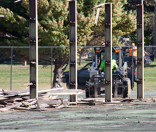 A worker with a skid loader clears away fencing and wooden debries from the dilapidated tennis courts at the Truax campus.