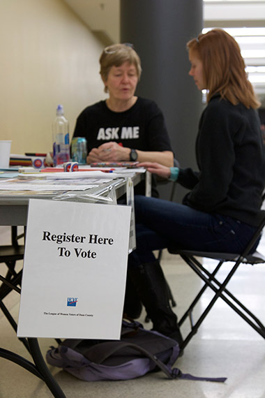 Gil Bliss, a volunteer from the League of Women Voters, helps a student register to vote at the Truax Campus.