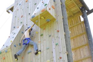 Patrick Kempfer scales the climbing wall with support from other members of the newspaper staff.