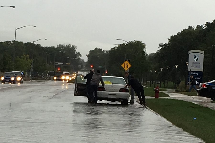 Students and officers push a stalled vehicle out of the flooded roadway on Sept. 7.