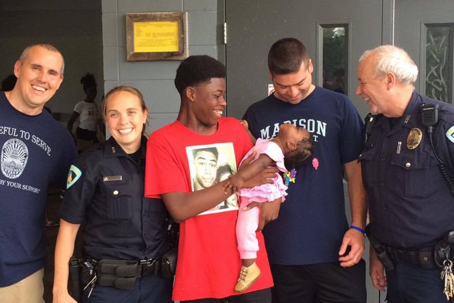 AJ Carr is holding his cousin, surrounded by MPD members including officer David Dexheimer (right)
