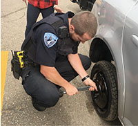  Below, Officer Weckerly helps a student in the Truax parking lot change a flat tire. 