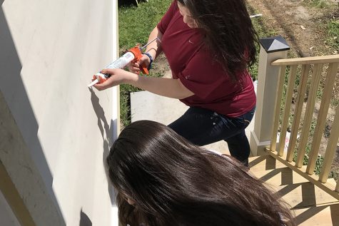 Two students caulk the exterior of a home during their alternative break trip to New Orleans.