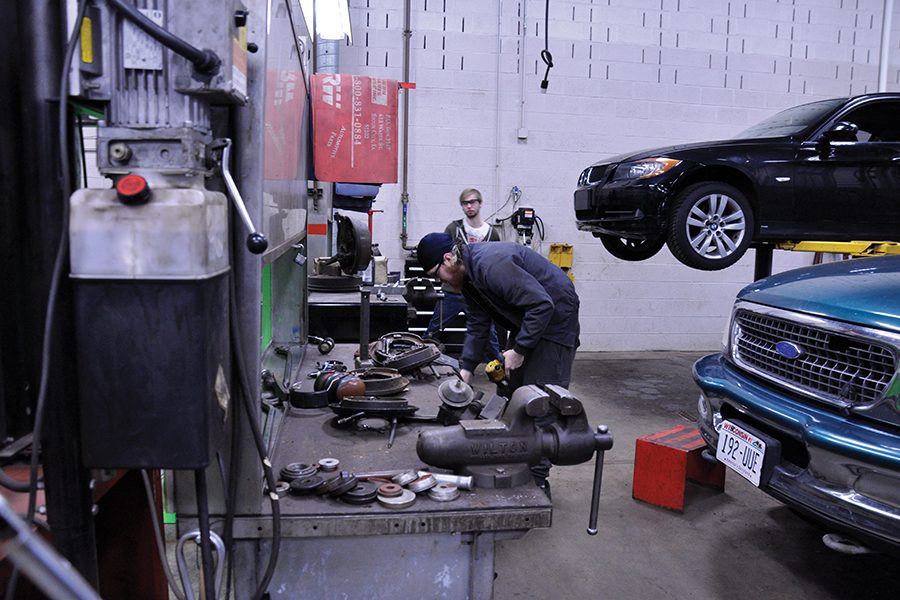 Two Madison College students work on a vehicle's brakes in one of the college's automotive bays during class.