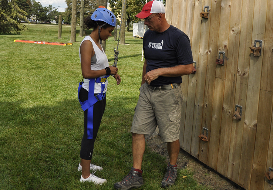 Jeff Messer, right, the Madison College Challenge Course Coordinator, shows student Lucy Smith how to properly attach her harness to the safety rope at the climbing wall. Messer works with groups of students, staff and guests who use the college’s outdoor challenge course to expand their learning experiences.