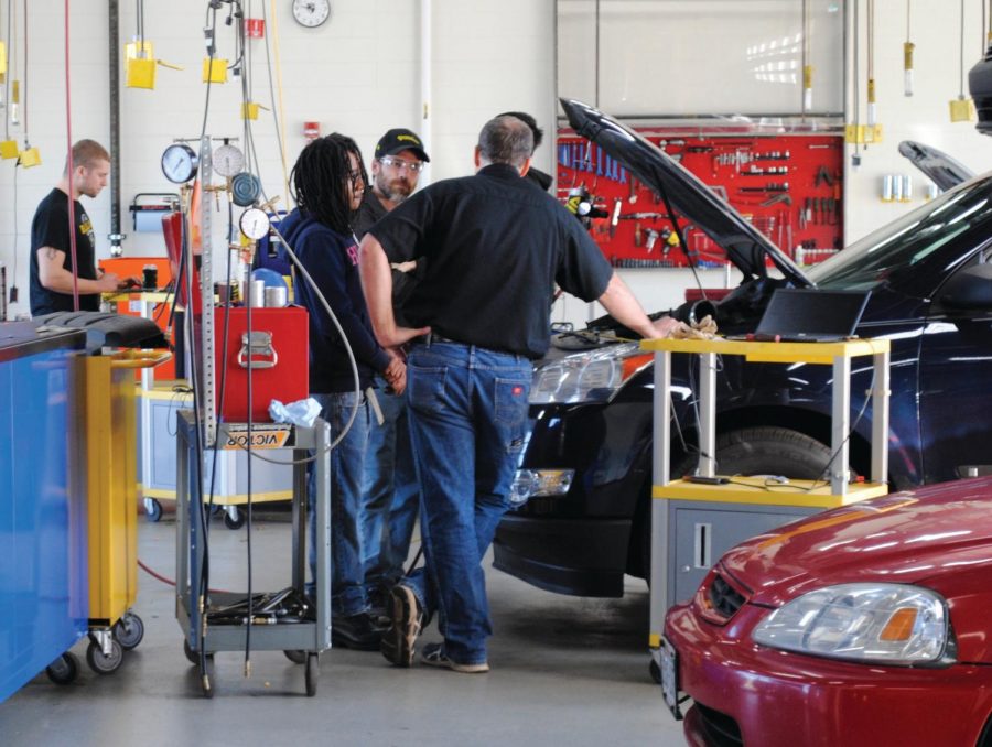 Students consult with instructors as they work on a vehicle inside one of the automotive bays at Truax.