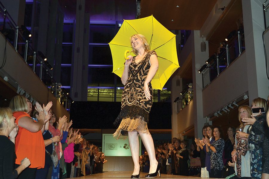 DAIS+Executive+Director+Shannon+Barry+walks+the+runway+in+the+DAIS+fashion+show%2C+carrying+a+yellow+umbrella+that+symbolizes+survival+from+domestic+abuse.