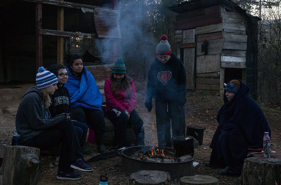 Students gather around a cooking fire in the Urban Slums during the alternative break trip to Heifer Ranch in Perryville, Arakansas.