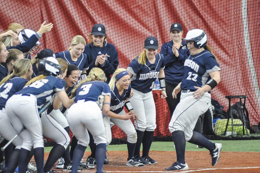 The entire dugout greets Katelin Gilbertson (22) at home plate after she hit a two-run homerun in the Madison College softball team’s season opening game against Rock Valley College, a 4-1 victory for the WolfPack.