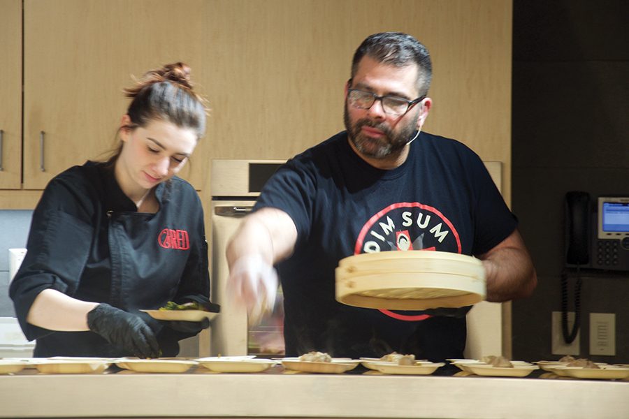 Culinary instructor Joe Gaglio works with a former student to serve dumplings at a recent chef series event.