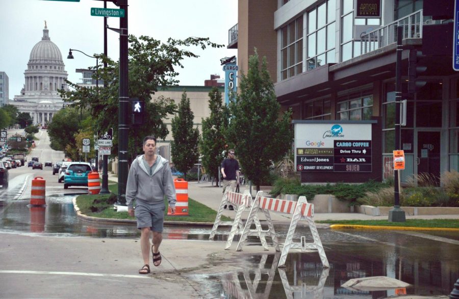 A pedestrian makes his way around the barricades protecting a flooded Livingston Street in downtown Madison on Sept. 7.