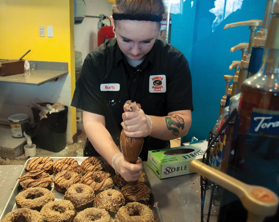 An employee of Hurts Donut decorates donuts before putting the out on the shelves. Hurts Donut will be joined by other vendors such as Fosdal Home Bakery and Lane’s Bakery at the second annual Dressed Up for Donuts fundraiser at the Old Sugar Distillery on Friday, Nov. 2, at 7 p.m.