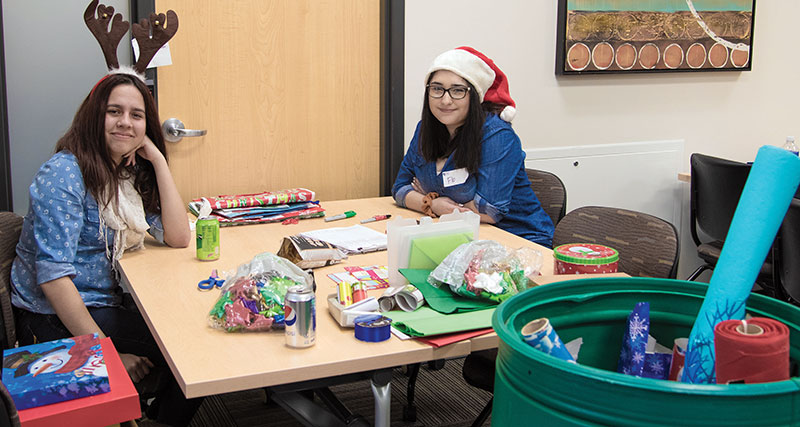 Volunteer Center event coordinator Florencia Balzano, right, and friend Mayra Puyol helped wrap gifts for the Santa’s Wish List program on Dec. 1.