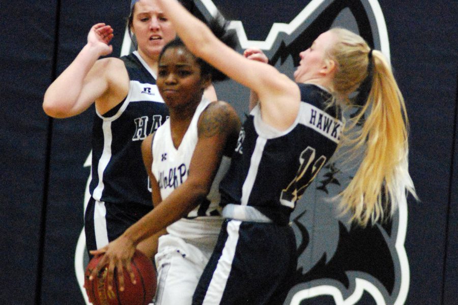 Women’s basketball player Shaquita Lee looks to pass the ball after being trapped by two Harper College opponents.