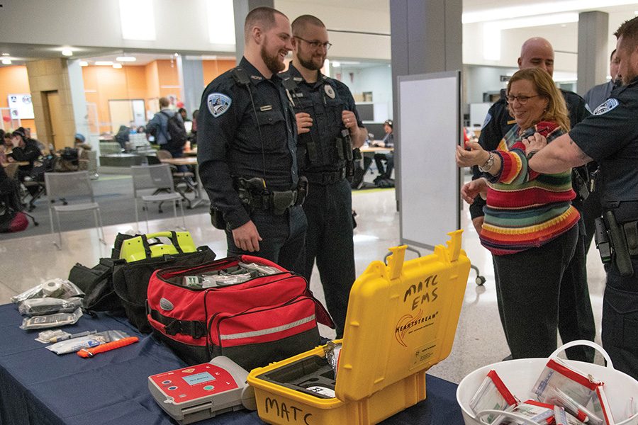 Public Safety officers demonstrate how to use a tourniquet to stop someone from bleeding during an event in the cafeteria