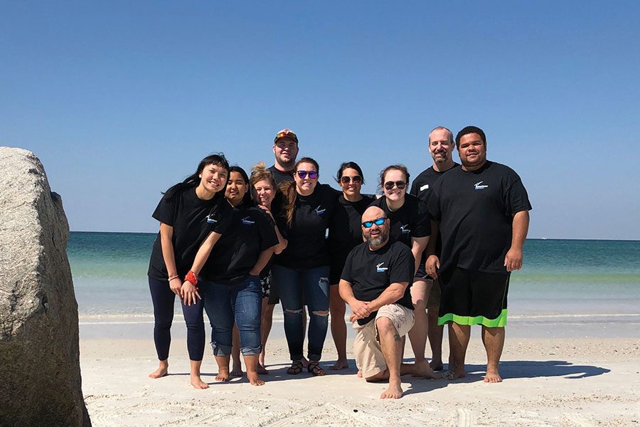 Madison College students and staff attending an alternative break service trip to the Florida panhandle gather for a photograph on the beach during a break in their work activities.