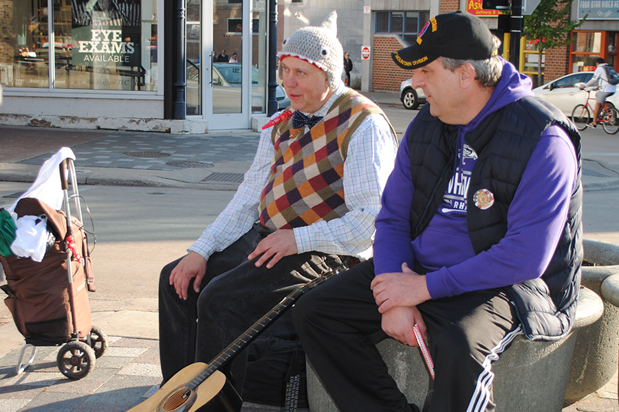 Brad Burt visits with a street musician during one of rounds visiting people along State Street in an attempt to connect with veterans who tend to frequent the area