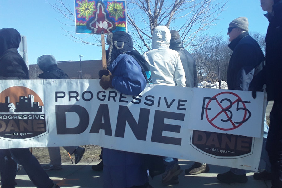 Protestors march past the Madison College Truax Campus on their way to the airport in opposition to plans to bring F-35 fighter jets to the Dane County Regional Airport.