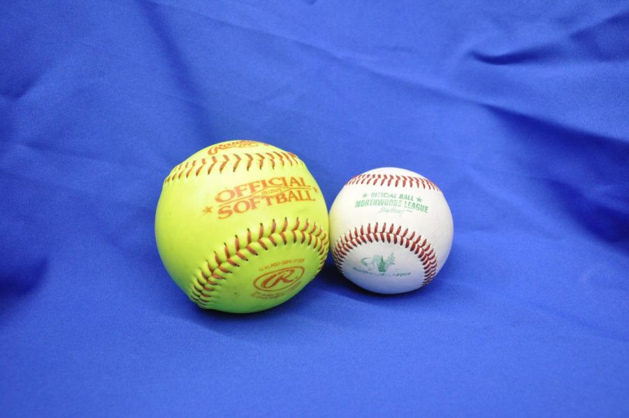 Size comparison of a softball next to a baseball.