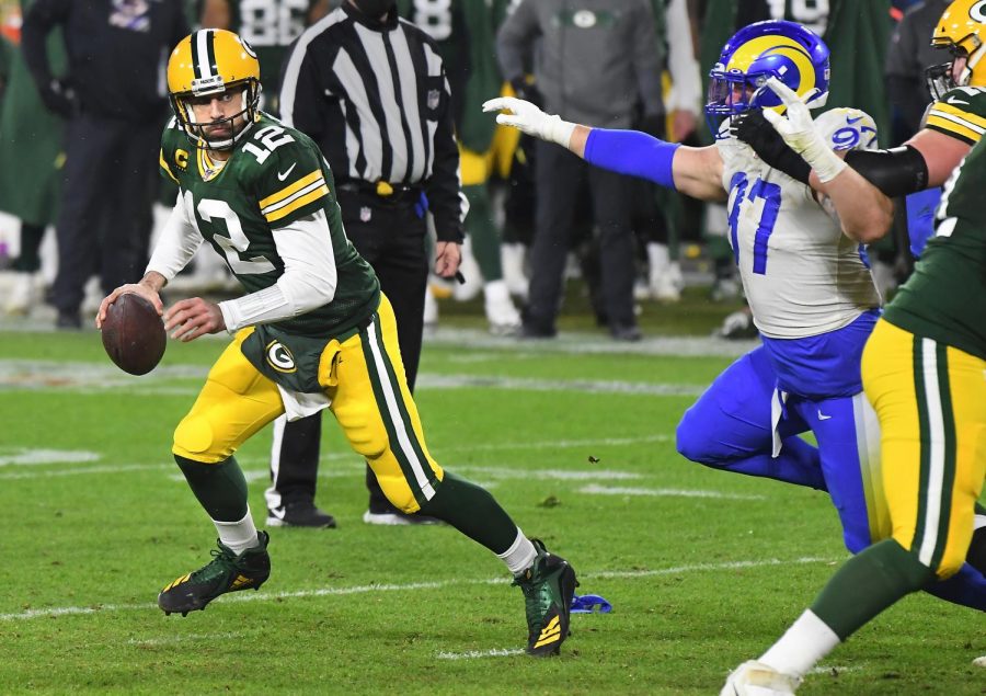 Green Bay Packers quarterback Aaron Rodgers (12) looks for a receiver as Los Angeles Rams defensive lineman Morgan Fox (97) pursues during an NFC Divisional playoff game at Lambeau Field in Green Bay on Jan. 16.