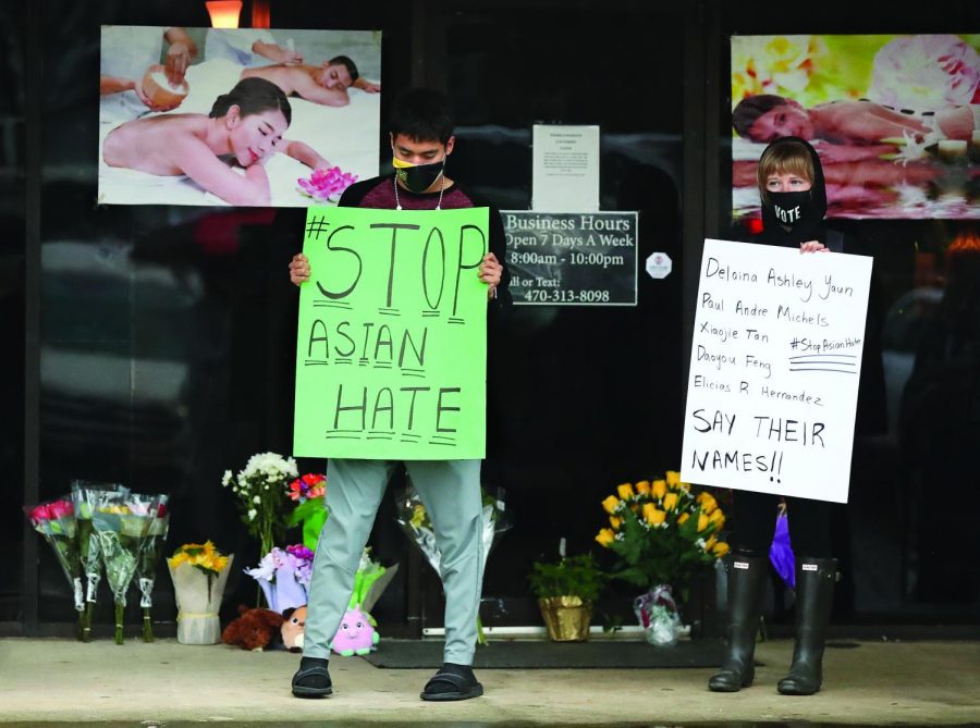 After dropping off flowers Jesus Estrella, left, and Shelby S., right, stand in support of the Asian and Hispanic community outside Youngs Asian Massage where four people were killed on Wednesday, March 17, 2021, in Acworth, Georgia.