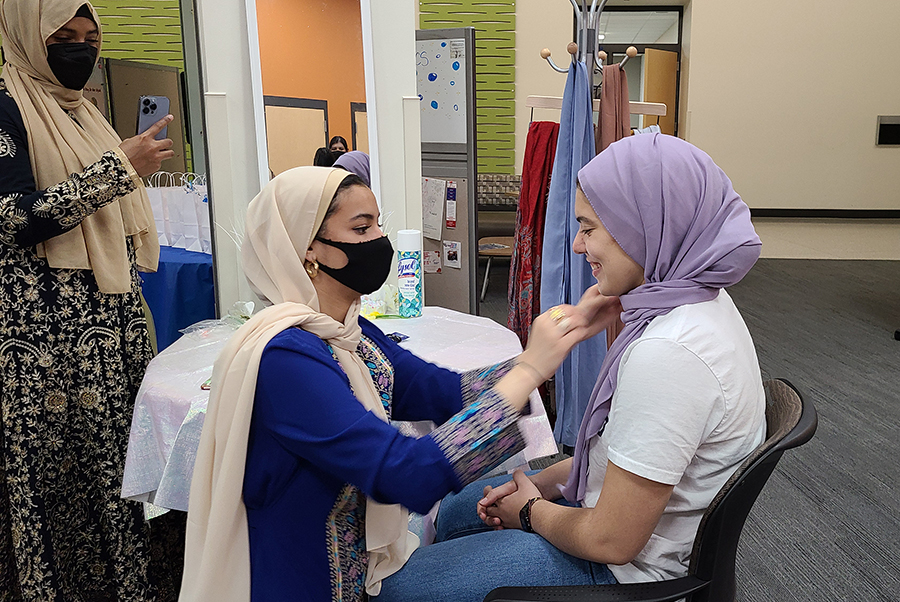 Ghaida Edris helps Deb Moreno, right, try on a hijab during an event in the Intercultural Exchange on Nov. 18.