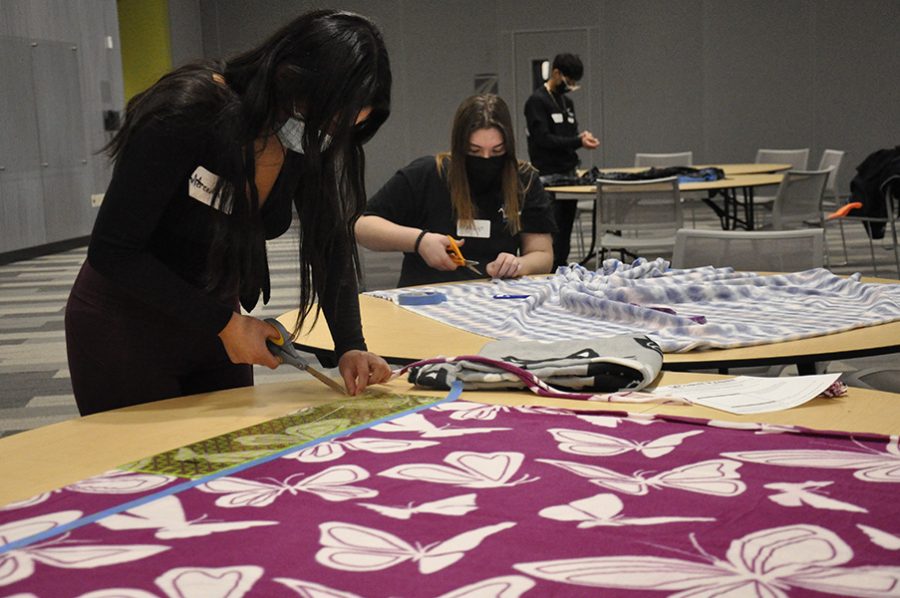 Students cut fabric to make blankets to donate to Project Linus during a Volunteer Center activity during winter break.