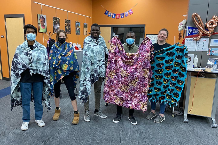 Volunteers display the blankets they made for Project Linus during one of the Alternative Break project days at Madison College.