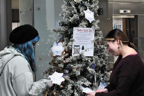 Student Life student employees Alyse Miller, left, and Levi Jones look at ornaments on the Volunteer Center’s giving tree.