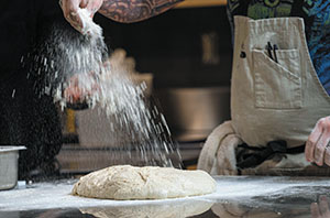 Greg Wade dusts a loaf of bread before putting it into an oven as part of the baking demonstration.