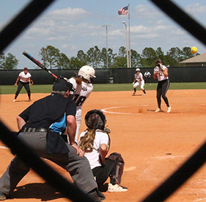 Madison College softball player Makenna Gish can be seen through the backstop taking a swing at a pitch during a game in Florida this month.