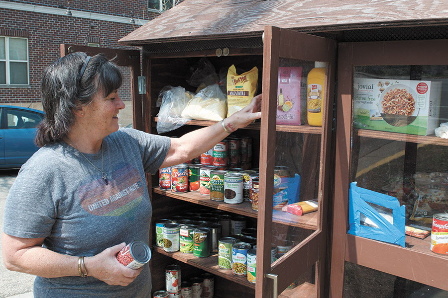 Kristin Mathews, a volunteer at the Willy Street Pantry since 2019, re-stocks the outdoor cabinet.