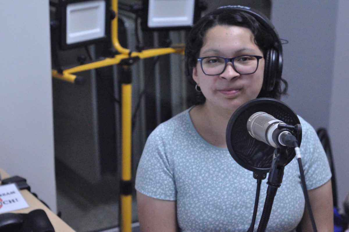 Subtítulo de la foto: Paola Ramos Ramírez, gerente general de Radio Clarion, trabaja en su programa en el estudio de radio de la universidad en la Oficina de Vida Estudiantil (Student Life Office), Sala Truax B1260. 