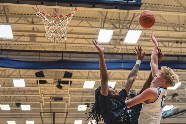 Photo of basketball player reaching over a defender for a shot.