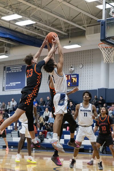 Photo of two basketball player reaching up for a rebound.