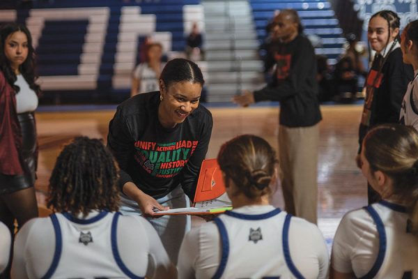 Photo of coach talking to women's basketball players.