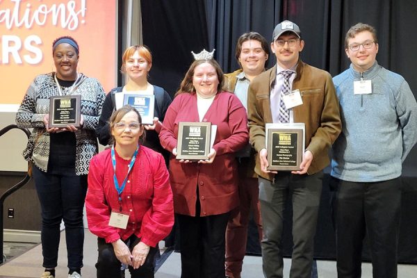 Image of a group of students on stage holding award plaques.