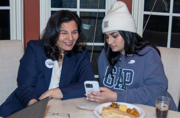 Photo of two women at a dinner table looking at a phone.