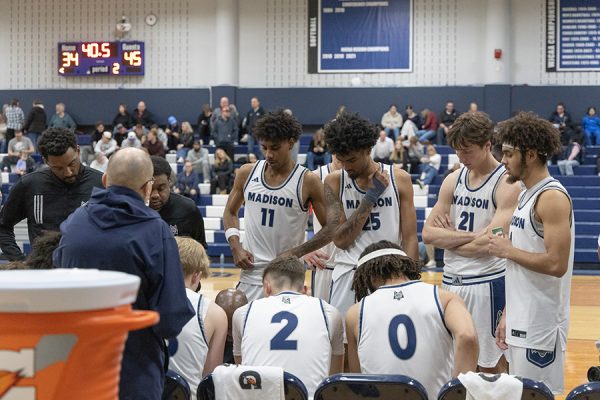 Photo of a men's basketball team in a huddle.
