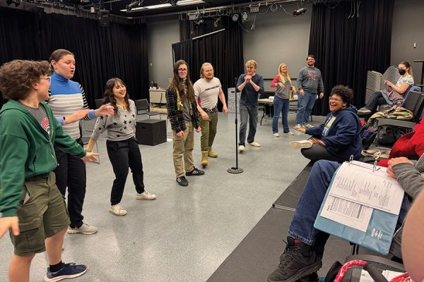 Several actors line up across a stage during play rehearsal.