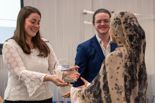 A female student presents an crystal award to another young lady.